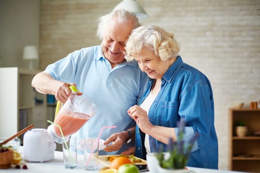 Affectionate senior couple making fruit smoothie in blender