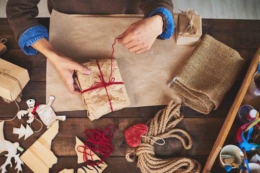 Hands of man tying up wrapped gift with woolen thread