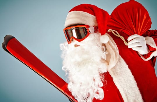 Santa Claus with red sack and ski equipment