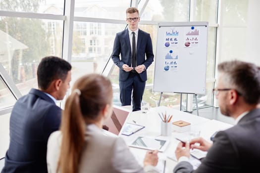 Young businessman standing by board and listening to his colleagues opinion about his presentation