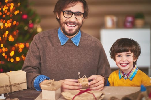 Happy young man and his son preparing Christmas surprises for friends