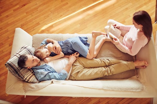 Modern family of three relaxing on sofa