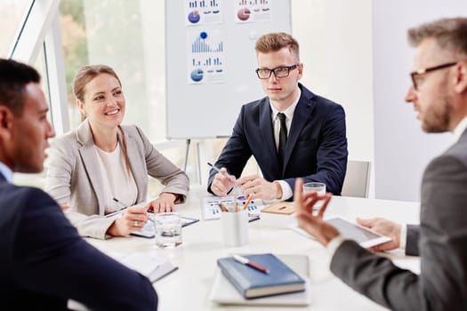 Group of confident colleagues interacting at meeting in office
