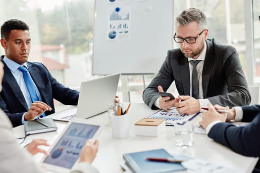 Businessmen using modern gadgets at meeting