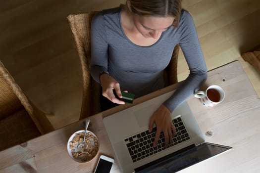 Ariel view of a woman using her laptop to make an online card payment.
