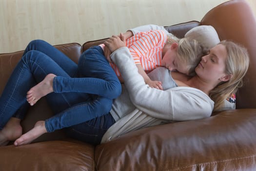 Ariel view of a mother and daughter having a nap together on a sofa.
