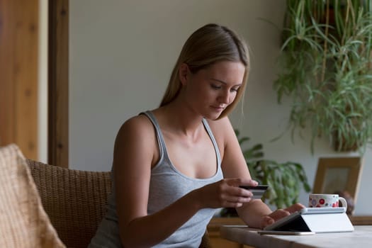 Woman using her digital tablet in her home to make an online card payment.