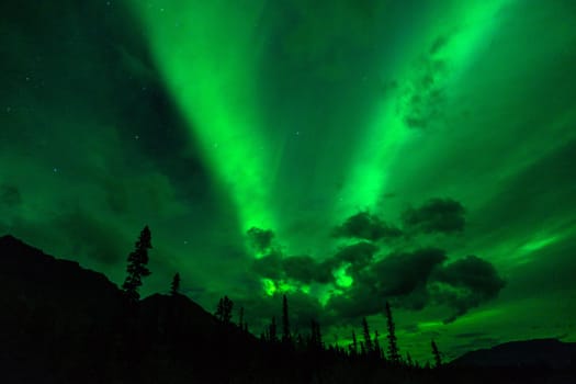 The Northern Lights emerge through the clouds in remote Alaska