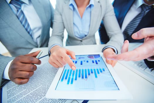 Group of employees discussing financial data in touchpad
