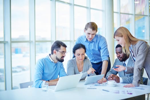 Group of employees consulting electronic data while making analysis