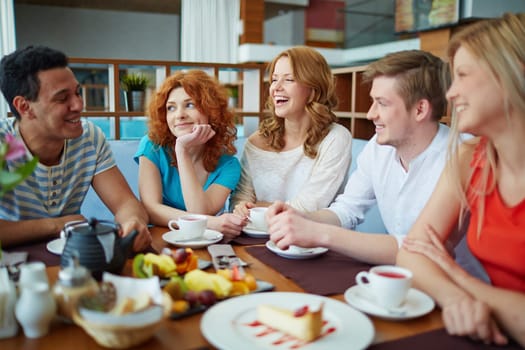 Happy friends talking while relaxing in cafe