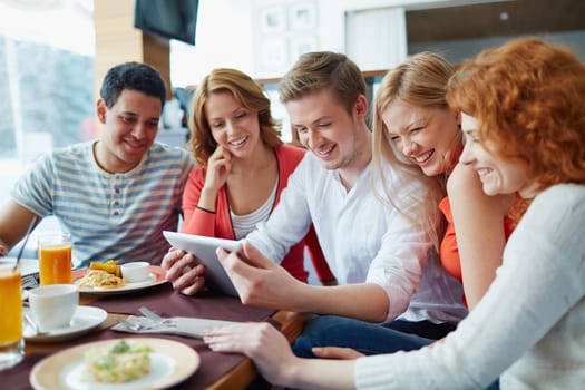 Friendly teens with touchpad spending leisure in cafe