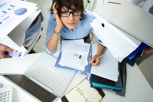 Anxious accountant surrounded by huge piles of documents held by her colleagues