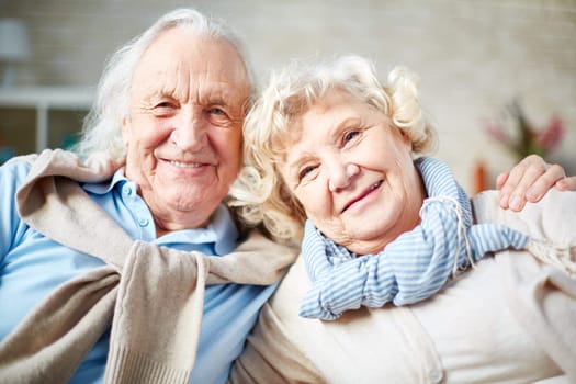 Affectionate elderly couple looking at camera with smiles