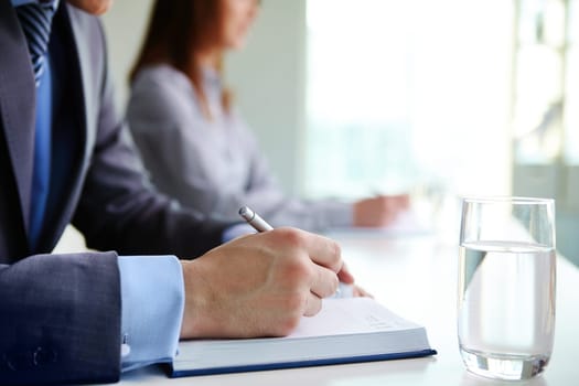 Male hand with pen writing in notebook