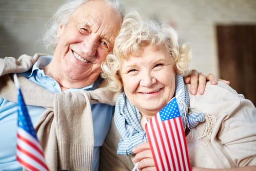 Smiling seniors with flags of USA looking at camera
