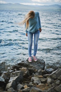 Young woman in jeans and pullover spending weekend by the seaside