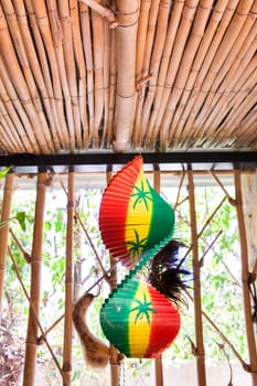 Hanging wooden spiral decorative craft with reggae color over open window of a tropical hut