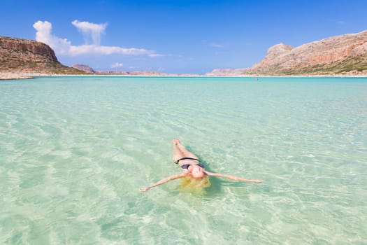 Beautiful Caucasian woman floating in turquoise blue lagoon.