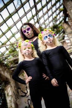 Woman and twin sisters with halloween makeup in abandoned house