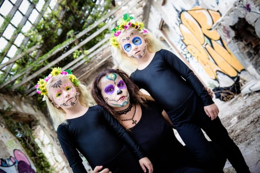Woman and twin sisters with sugar skull makeup in abandoned house