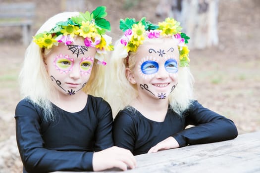 Twin girls in black clothing with sugar skull makeup smiling