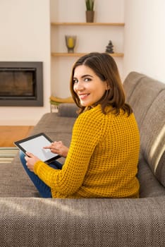 Beautiful young woman working with a tablet at home