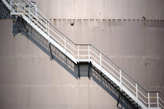 The top edge of a water tank with a walk-in ladder that casts a shadow.