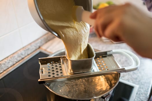 Hand with dough and late tin over cooking pot