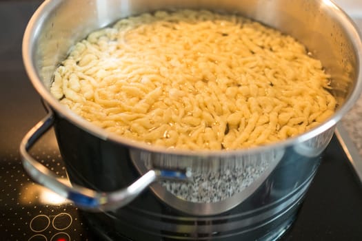 Spätzle in the water in a cooking pot on a stove