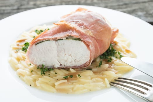 Turkey breast in bacon coat on rice noodles with parsley