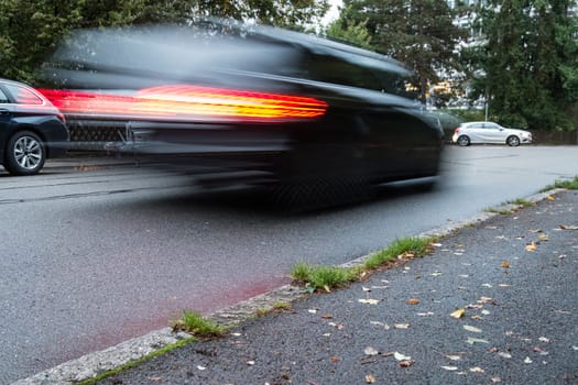 Blurred car with red taillight on a road