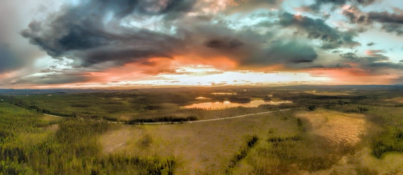 Huge storms colored by sunset above the forests in Sweden, aerial panorama