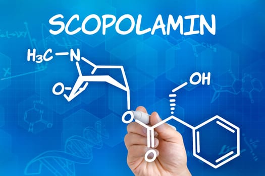 Hand with pen draws chemical structural formula of scopolatain