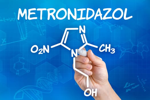 Hand with pen draws chemical structural formula of metronidazole