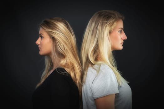 2 blonde women stand back to back