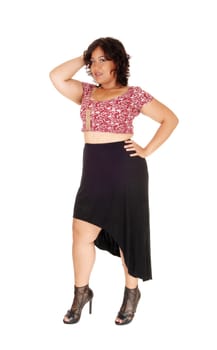 A mixed raced young woman standing isolated for white background.in a black skirt, in profile with one hand on head..