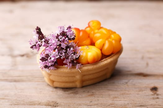 Cloudberry tart decorated with wild marjoram. Sweet baked dessert with fresh wild cloudberries on a wooden table.