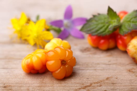 Cloudberries (moroshka) on a wooden table. Wild northern berry. Shallow depth of field