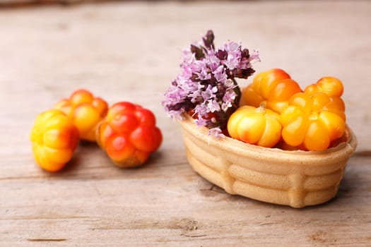 Cloudberry tart decorated with wild marjoram. Sweet baked dessert with fresh wild cloudberries on a wooden table.