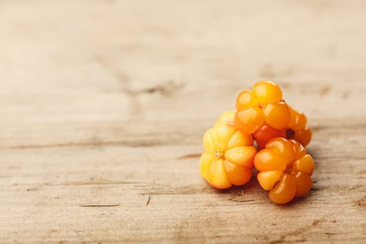 Cloudberries (moroshka) on a wooden table. Wild northern berry. Shallow depth of field