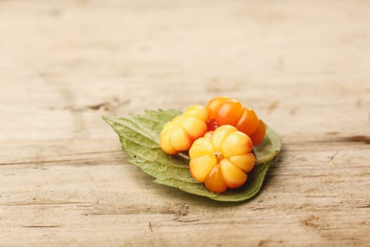 Cloudberries (moroshka) on a wooden table. Wild northern berry. Shallow depth of field