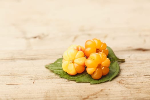 Cloudberries (moroshka) on a wooden table. Wild northern berry. Shallow depth of field