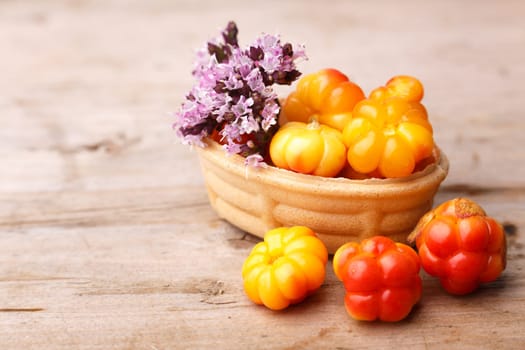 Cloudberry tart decorated with wild marjoram. Sweet baked dessert with fresh wild cloudberries on a wooden table.