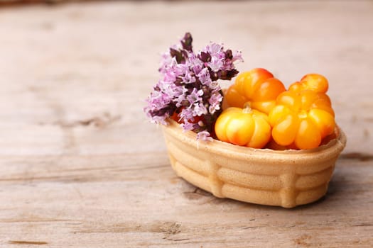 Cloudberry tart decorated with wild marjoram. Sweet baked dessert with fresh wild cloudberries on a wooden table.