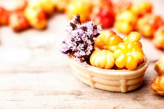 Cloudberry tart decorated with wild marjoram. Sweet baked dessert with fresh wild cloudberries on a wooden table. Instagram filter styled