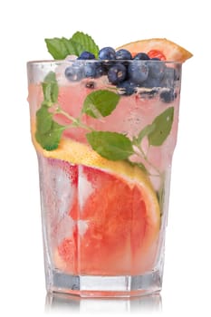 Grapefruit mojito cocktail in faceted highball garnished with blueberry. Refreshing summer drink with rum,grapefruit and fresh mint