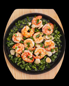 Grilled shrimps on a frying pan with chopped leek