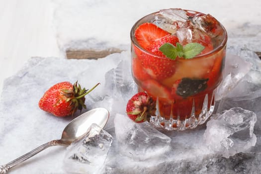 Strawberry mint bourbon smash served on a marble plate with crushed ice . Alcoholic cocktail with strawberry.
