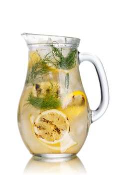 Carbonated iced detox water with grilled lemon wheels and fresh dill stems in a glass pitcher